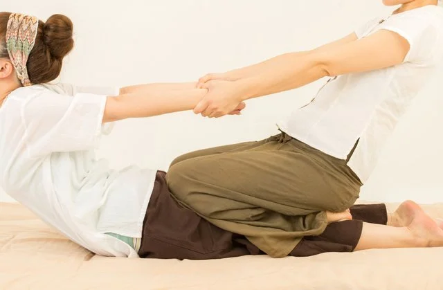 セラピストが脚を支えながらゆっくり伸ばしていくタイ古式ストレッチの施術